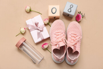 Composition with sports shoes, bottle of water, gift box and flowers on color background. International Women's Day