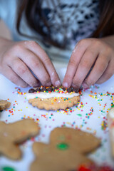 Little hands decorating a Christmas cookie with hundreds and thousands and festive happiness and love.