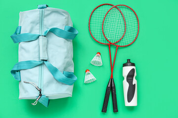 Sport bag, badminton racket and water bottle on green background