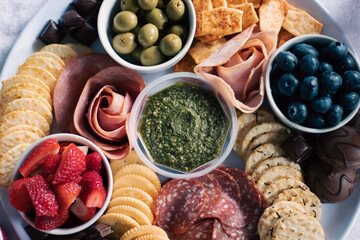 An artisanal, antipasto, fresh fruit, meat, and cracker grazing board finger food, with...
