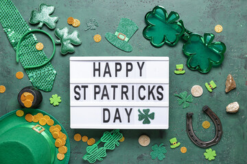 Board with words HAPPY ST PATRICKS DAY, leprechaun hat and decor on green grunge background