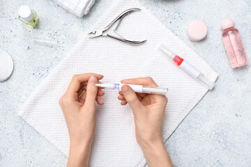 Female hands with cuticle oil pens, towel and cutter on blue grunge background