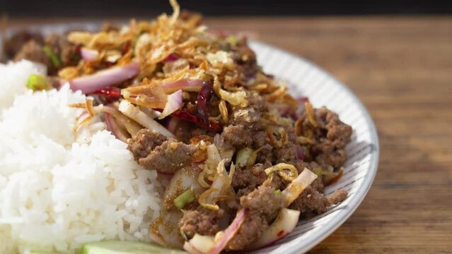 Laos National Dish Beeef Larb, plated beef onion rice dish with cucmbers, slider close up 4K