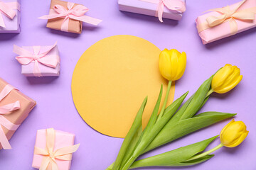 Gift boxes, yellow tulips and blank greeting card on lilac background. Top view