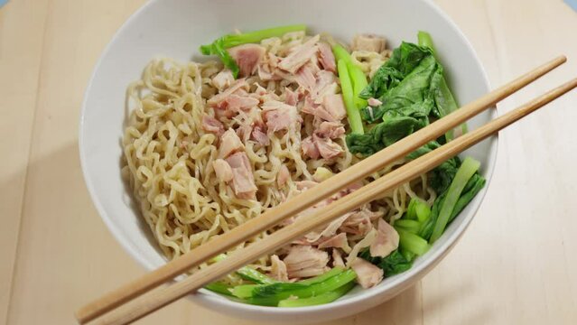 Chopsticks On A Bowl Of Bakmi Wheat Noodles Served With Bok Choy And Meat. closeup, rotating