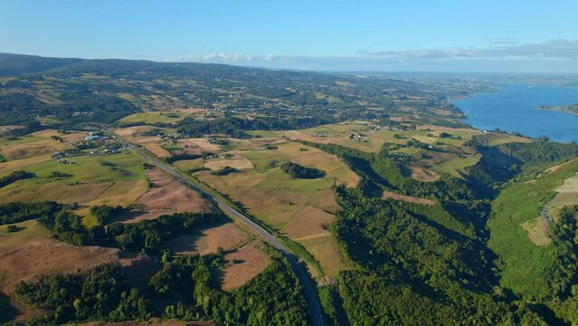 Aerial shot of Chiloé Island in Chile with lush landscapes and coastal view, sunlight