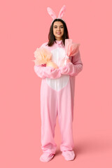 Beautiful young woman in bunny costume with Easter gift eggs on pink background