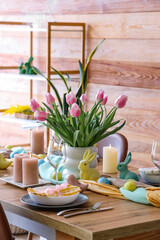 Beautiful Easter table setting with vase of tulips, cutlery and painted eggs