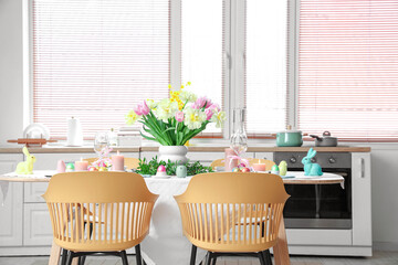 Modern interior of festive decorated kitchen with Easter table setting, window and chairs