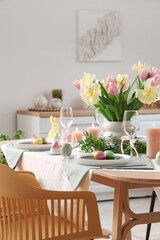Festive Easter table setting with vase of flowers, cutlery, napkins and painted eggs