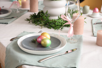 Stylish Easter table setting with cutlery, candles and painted eggs