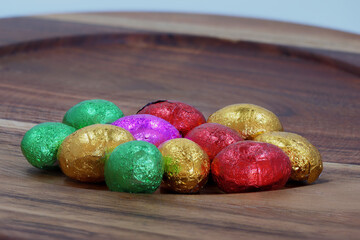 Foil wrapped mini easter eggs on a wooden board