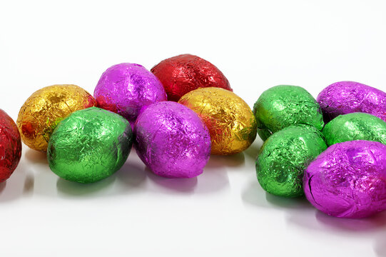 A close up image of foil wrapped mini Easter eggs with a white background