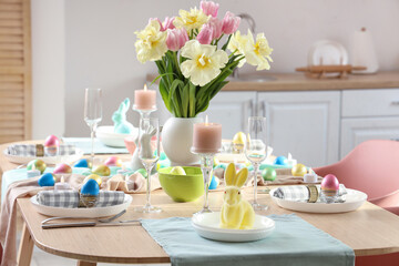 Stylish Easter table setting and vase of flowers in room