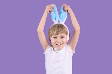 Cute little boy in bunny ears on purple background. Easter celebration