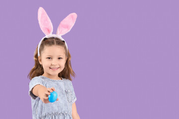 Cute little girl in bunny ears with Easter egg on purple background