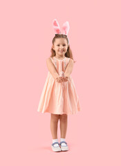Cute little girl in bunny ears with bird on pink background. Easter celebration