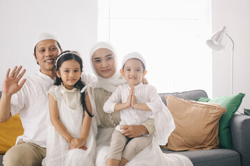 Portrait of happy muslim family sitting on the sofa in living room.