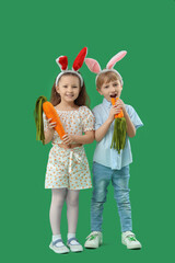 Cute little children in bunny ears with toys carrots on green background. Easter celebration