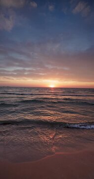 Sunset tropical beach shore and splashing waves on the sea sand vertical slow motion 4k video