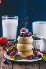 Cheesecakes served with berries and condensed milk