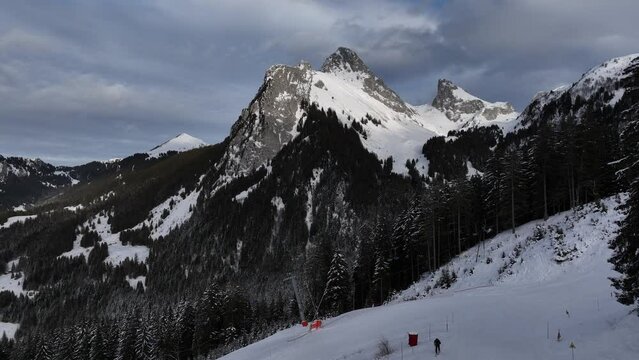 Tilt up on beautiful mountain summit with snow and vast sky of clouds, French Alps