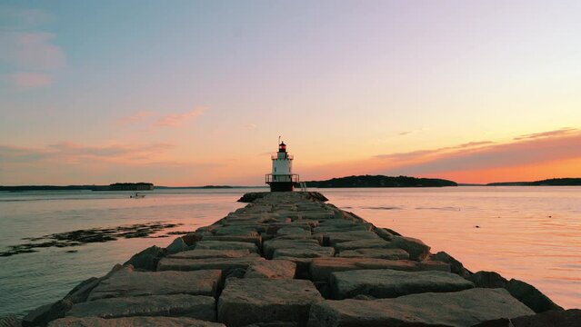 Sunrise at Spring Point Ledge Lighthouse with serene sky, showcasing beautiful orange and yellow clouds