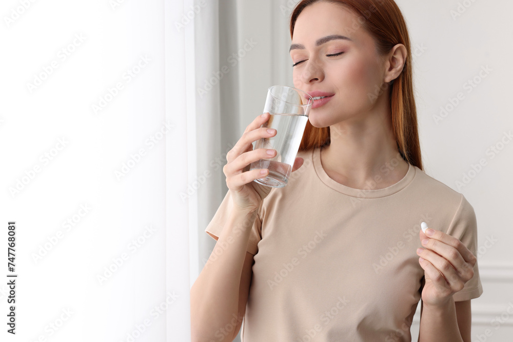 Poster beautiful young woman with vitamin pill and glass of water. space for text