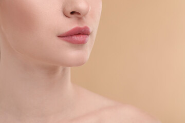 Obraz na płótnie Canvas Young woman with beautiful full lips on beige background, closeup