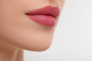 Young woman with beautiful full lips on white background, closeup