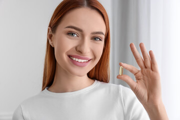 Beautiful young woman with vitamin pill at home