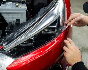 The process of applying protective vinyl film to car headlights in detailing. 