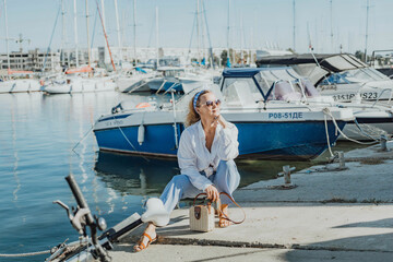 Woman in white shirt in marina , surrounded by several other boats. The marina is filled with boats of various sizes, creating a lively and picturesque atmosphere.