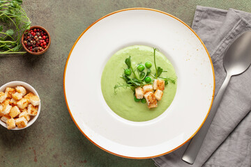 Green peas cream soup with croutons in plate. Summer vegetable food. Top view