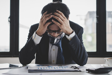 Business failure concept. Businessman sitting at his table in office and covering his face feel...