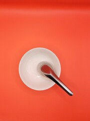 Top view of soup bowl and spoon on red background.