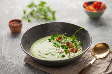 Green peas cream soup with bacon in bowl. Summer vegetable food