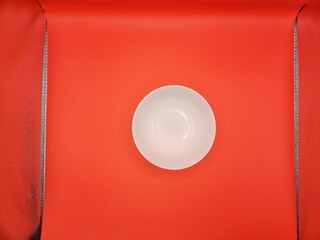 Top view of a white bowl in red background.