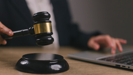 Woman judge hand holding gavel to bang on sounding block in the court room.