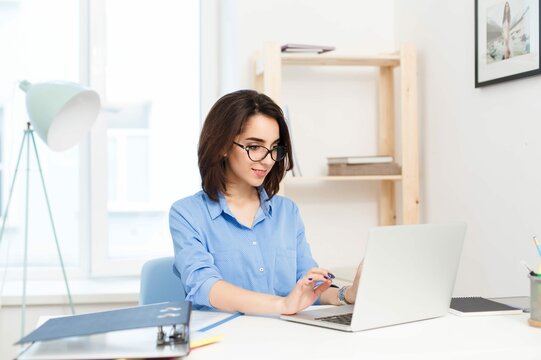 Pretty Brunette Girl Blue Shirt Sitting Table Office She Is Typing Laptop Looks Happy