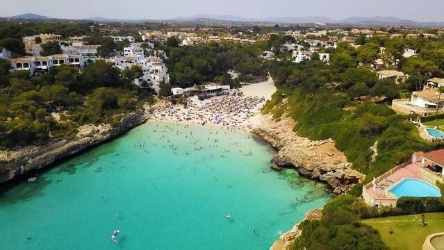 Retreating drone shot of the Cala Anguila Cove beachfront, a perfect getaway located in the island of Mallorca, off the coast of Spain in the Mediterranean Sea.