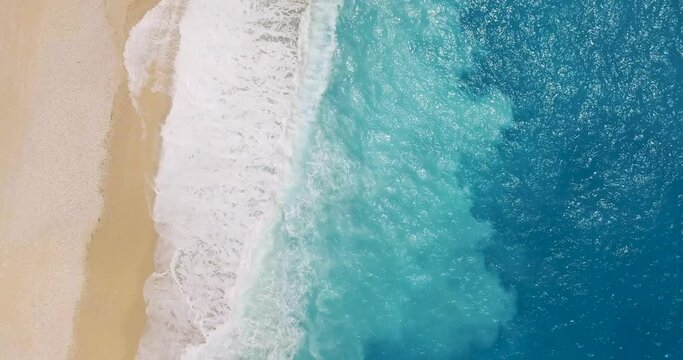 Myrtos beach with a single person lying on the sand, turquoise waves lapping the shore, aerial view