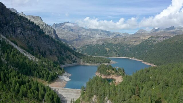 Lago di devero in alpe devero with clear waters surrounded by alpine trees and rugged mountains, aerial view
