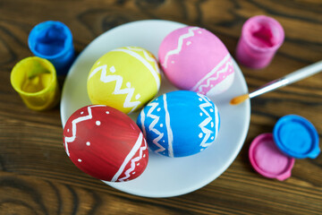 Fototapeta na wymiar Easter eggs painted in bright colors with a brush on a wooden background. Master class for children.