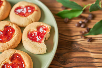 Cookies with strawberry jam on a plate on a wooden background.