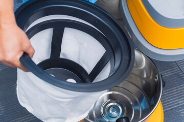 A janitor removes the inner dust filter bag from a commercial grade vacuum cleaner.