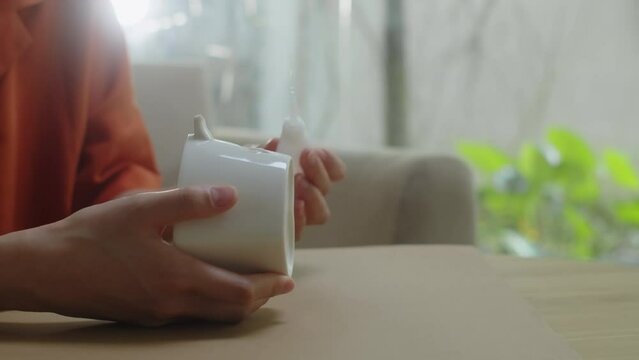 Close up of hands of person adding glue while repairing broken mug at home