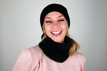 Captivating Brunette with Blue Eyes in Pink Shirt, Styled with Black Beanie and Scarf on White Background