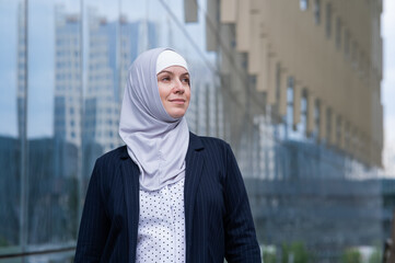 Portrait of smiling business woman in hijab and suit outdoors. 