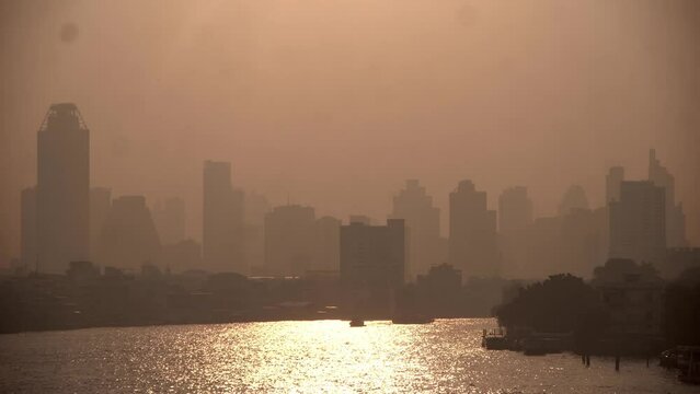 The cityscape of Bangkok is obscured by a thick blanket of dust and pollution . The heavy air pollution, filled with fine particulate matter (PM2.5), creates a hazy and oppressive atmosphere. 